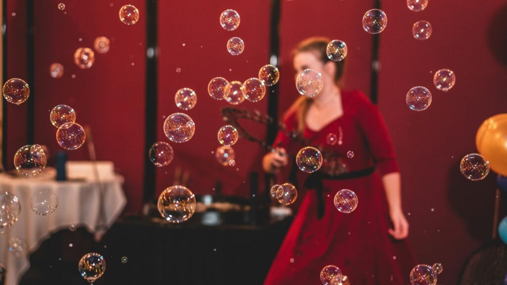 Indoor celebration with colorful bubbles floating around a person in a red dress.